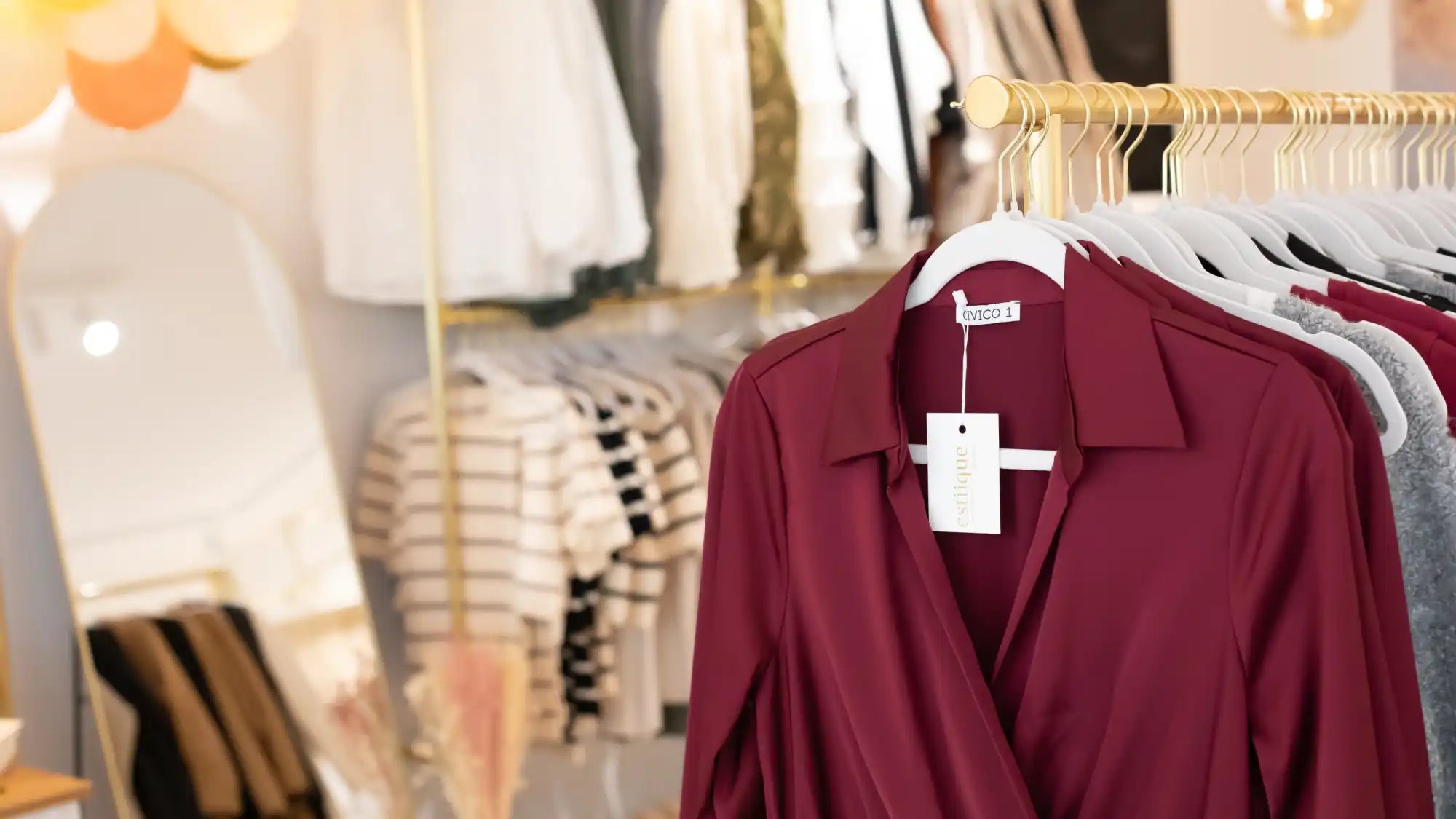 Bordeaux-Bluse mit weißem Etikett, hängend auf goldenem Bügel.