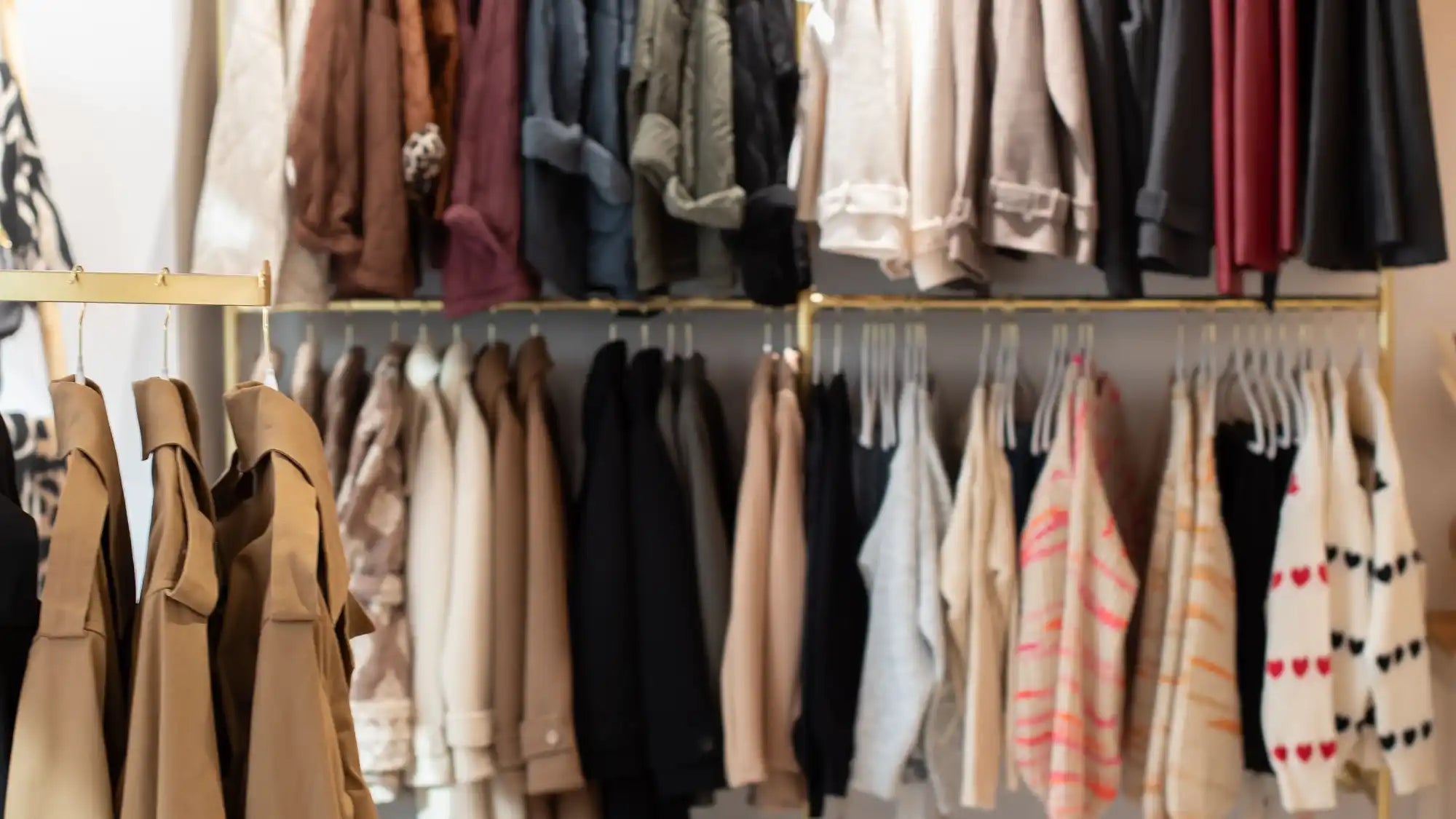 Bunt gefärbter, texturierter Pulloverständer mit goldenen Metallhaken und Bügeln.